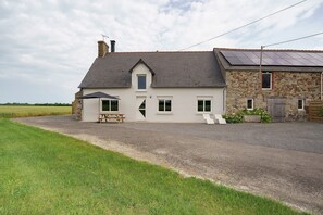 Une maison à deux étages avec une allée en gravier, une table de pique-nique et un petit jardin.