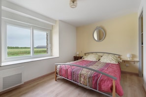 Une chambre à coucher avec un lit, une fenêtre, une table de chevet et un miroir.