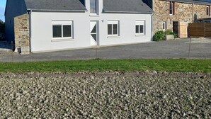 Une maison à deux étages, avec un toit en pente, une cheminée et une façade en pierre.