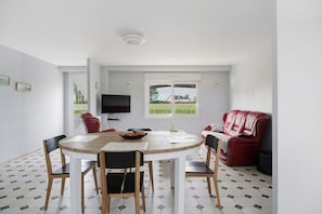 Ein Essbereich mit einem runden Tisch, Stühlen und einem roten Sofa.