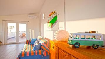 A room with a sofa, a wooden cabinet, a toy bus, and a wall-mounted sign.