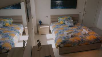 A bedroom with two beds, a nightstand, a lamp, and a painting on the wall.
