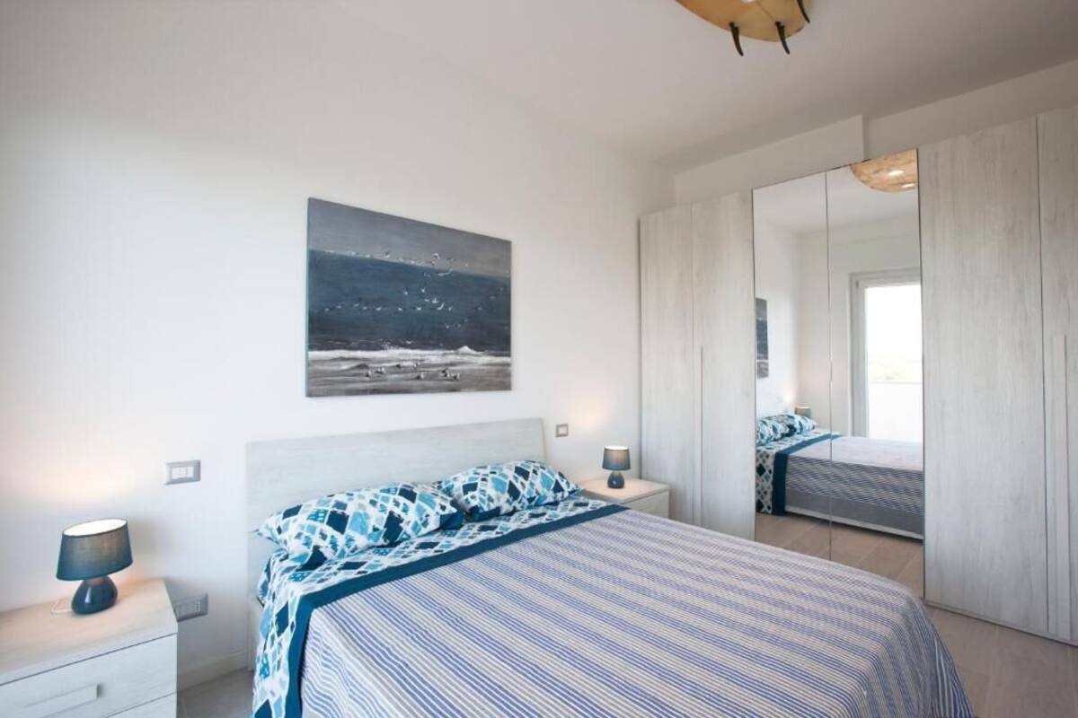 A bedroom with a bed, a nightstand, a lamp, a painting, and a mirror.