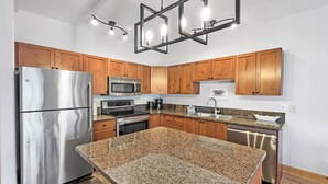 A modern kitchen with granite countertops, stainless steel appliances, and wooden cabinets.