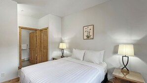 A hotel room with a large bed, two bedside tables with lamps, a wooden wardrobe, and a framed picture on the wall.