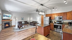 A modern kitchen with a central island, built-in appliances, and a dining area with a fireplace.