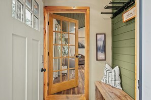 A wooden door with a glass panel, a bench with pillows, a framed picture, and a sign on the wall. - Luxury Pocono Escape Spacious Home w/ Sauna, Hot Tub & Mini Golf (Tobyhanna)