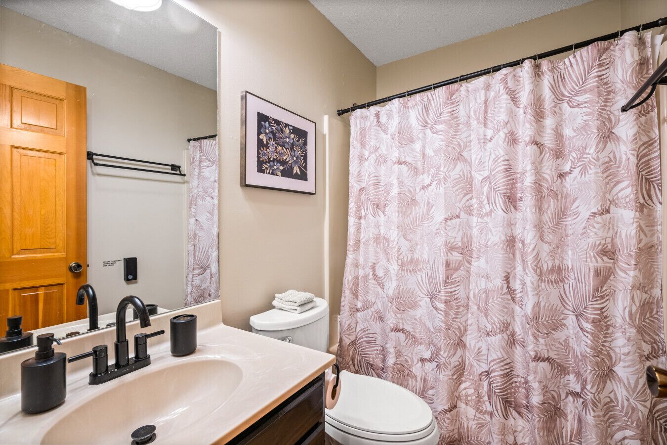 Un bagno con lavandino, specchio, WC e tenda della doccia.
