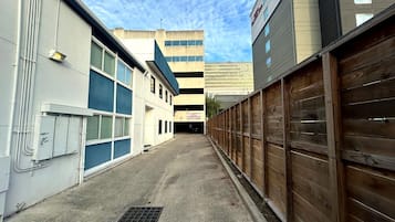 Un callejón estrecho entre edificios, con una puerta de garaje a la derecha y un edificio de fachada azul a la izquierda.