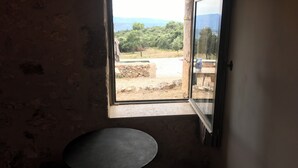 Una stanza con una finestra, un tavolo rotondo e una panca di legno.