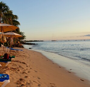 Una playa con sombrillas, sillas de descanso y un mar tranquilo.