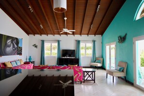 Una sala de estar con un sofá, televisión y un ventilador de techo.