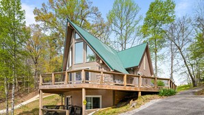 A cabin with a green roof, a balcony, and a porch with outdoor seating. - Old Rocky: 824 Deerfield Way (LaFollette)