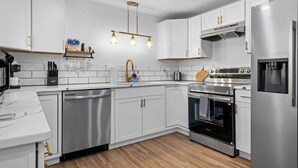 A modern kitchen with white cabinets, stainless steel appliances, and a wooden countertop. - Sleeps 16 • Hot Tub • Egg Chairs • Pool Table • 4 bedroom • Near New River Gorge (Oak Hill)