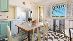 A kitchen with a dining table, chairs, a dishwasher, and a window with a view. - Villetta Sole e Sale - Trilo by BarbarHouse (Campomarino)