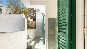 A narrow outdoor corridor with a green door, a white wall, and a tiled floor. - Villetta Sole e Sale - Trilo by BarbarHouse (Campomarino)
