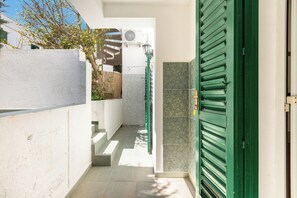 A narrow outdoor corridor with a green door, a white wall, and a tiled floor. - Villetta Sole e Sale - Trilo by BarbarHouse (Campomarino)