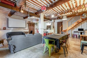 Una sala de estar acogedora con sofá, mesa de comedor, sillas y una escalera.