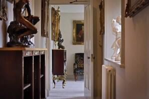 A hallway with ornate furniture, a painting, and a statue. - Morland Manor (Peterborough)