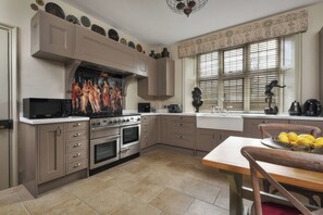 A kitchen with a stove, oven, microwave, and a dining area with a table and chairs. - Morland Manor (Peterborough)