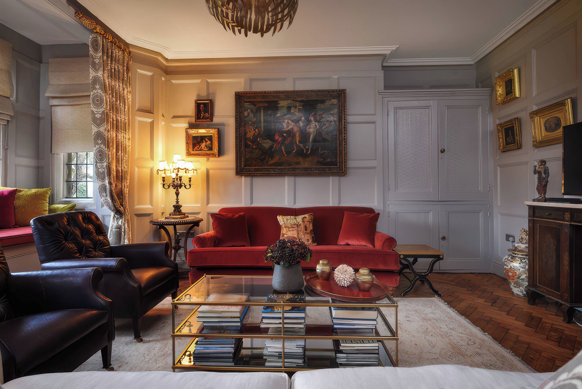 A living room with a red sofa, black leather armchair, and a glass coffee table with books.