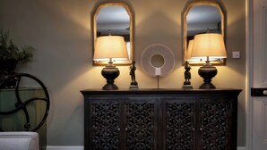 Un mobile scuro in legno con due lampade e due specchi sopra.