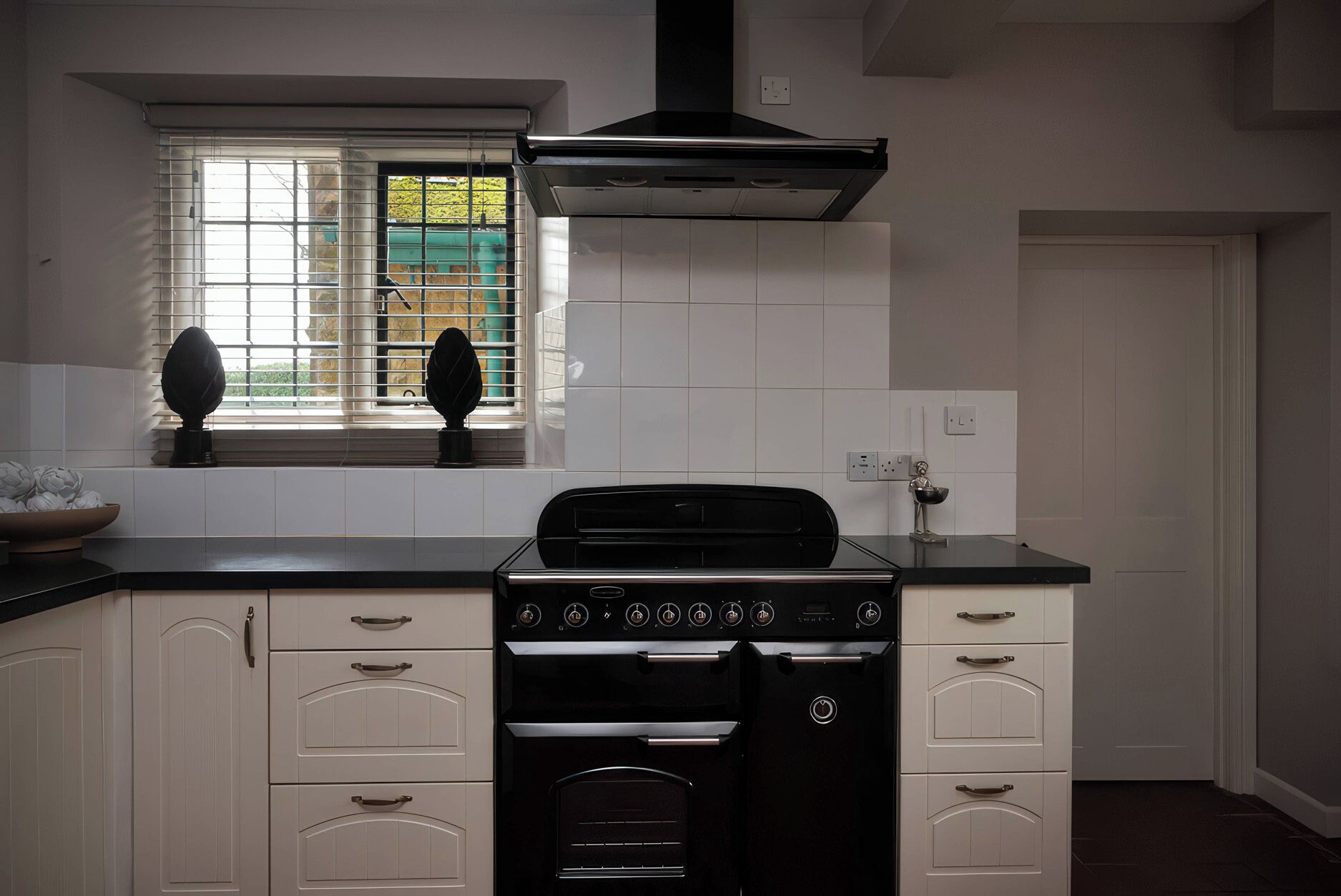 A kitchen with a stove, oven, and window with blinds.