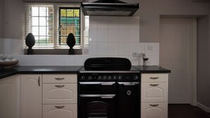 Una cucina con fornello, forno e finestra con persiane.