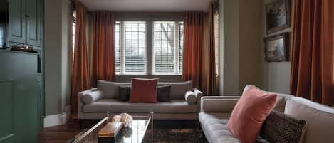 A living room with a sofa, a coffee table, and a window with curtains.