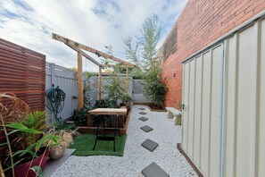 A backyard with a wooden pergola, a table, and a garden area with stepping stones. - Peace and Love 2 BDR Townhouse West Melbourne (West Melbourne)
