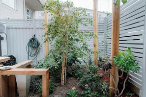 A garden with a wooden trellis supporting a climbing plant, surrounded by various potted plants and a wooden table. - Peace and Love 2 BDR Townhouse West Melbourne (West Melbourne)