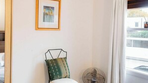 A room with a bed, a framed picture on the wall, a standing fan, and a window with curtains. - Peace and Love 2 BDR Townhouse West Melbourne (West Melbourne)