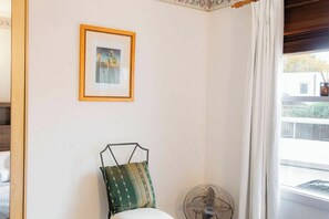 A room with a bed, a framed picture on the wall, a standing fan, and a window with curtains. - Peace and Love 2 BDR Townhouse West Melbourne (West Melbourne)