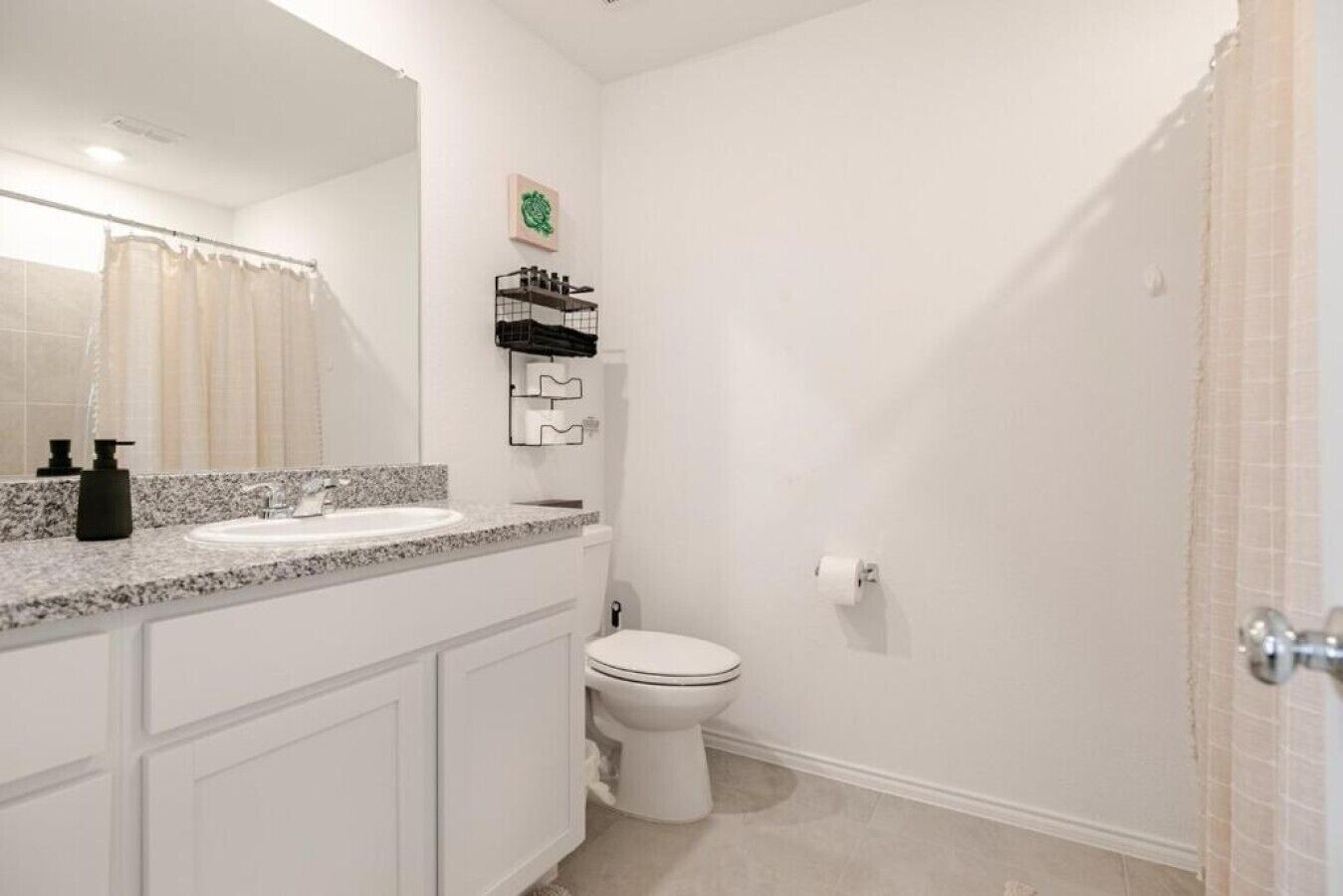 A bathroom with a white sink, a toilet, a shower area, and a towel rack.
