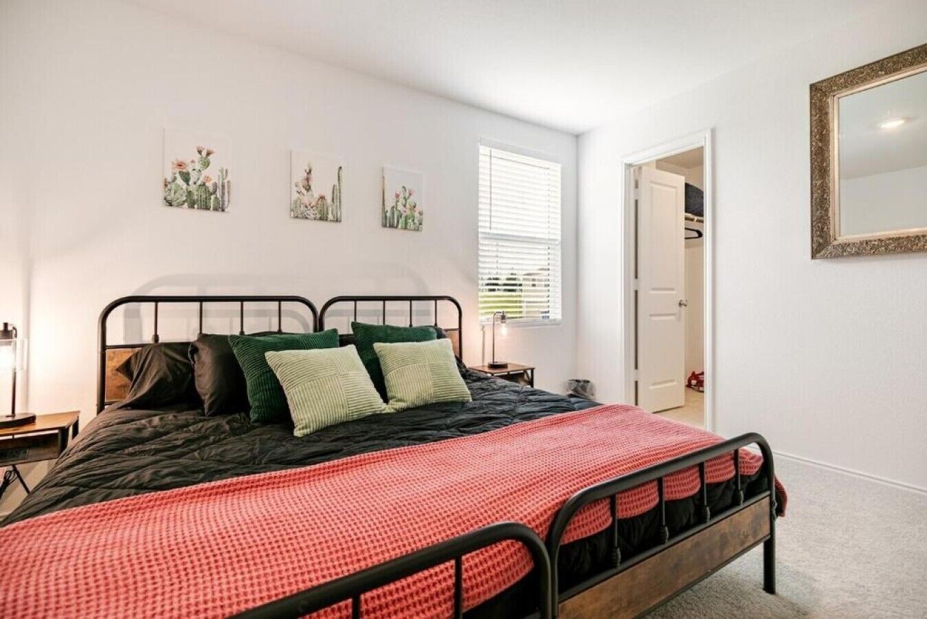 Une chambre à coucher avec un lit, des oreillers, une table de chevet, une fenêtre avec des stores et une porte.
