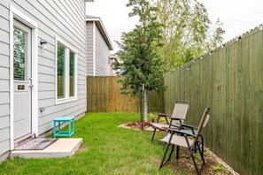 A backyard with a wooden fence, a small tree, and two chairs. - 4bd/2.5bth, 8 guests, Pet friendly (Dallas)