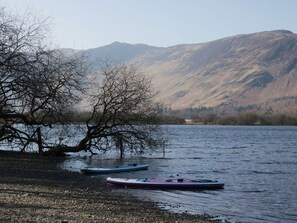 A calm lake with kayaks on the shore, surrounded by mountains. - Fellfoot Cottage (Cockermouth)