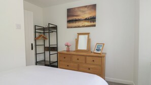 Une chambre à coucher avec un lit, une commode, un miroir, un cadre photo et un tableau accroché au mur.