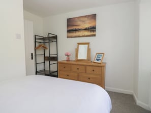 Ein Schlafzimmer mit einem Bett, einer Kommode, einem Spiegel, einem Bilderrahmen und einem Gemälde an der Wand.