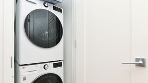 A stacked washer and dryer unit in a white utility room. - Sleek 2BR Oasis in NYC Financial District (New York)