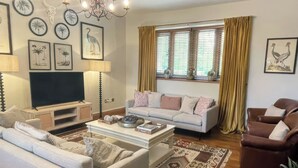 Sala de estar com sofá, poltrona, televisão e arte decorativa na parede.