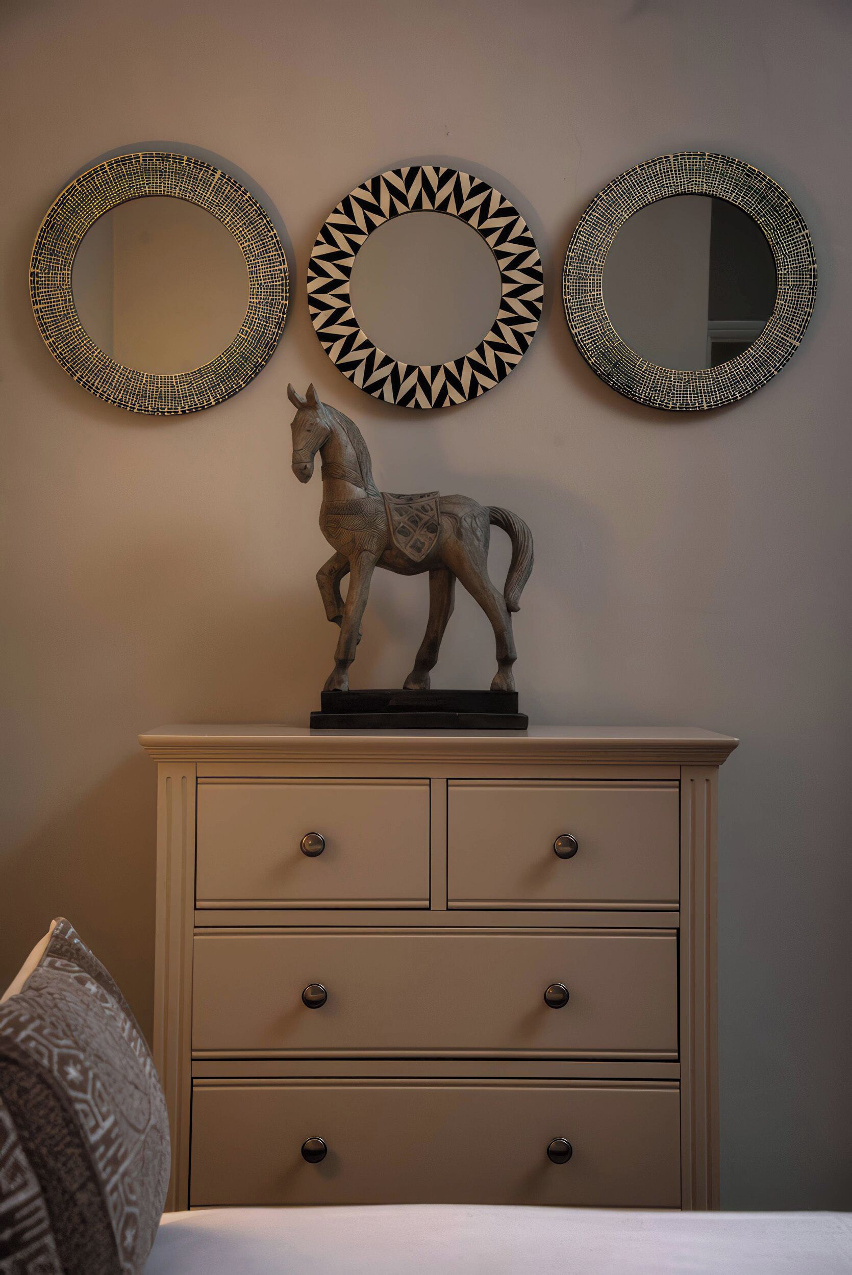 Une commode à trois tiroirs, sur laquelle est posée une statue de cheval.