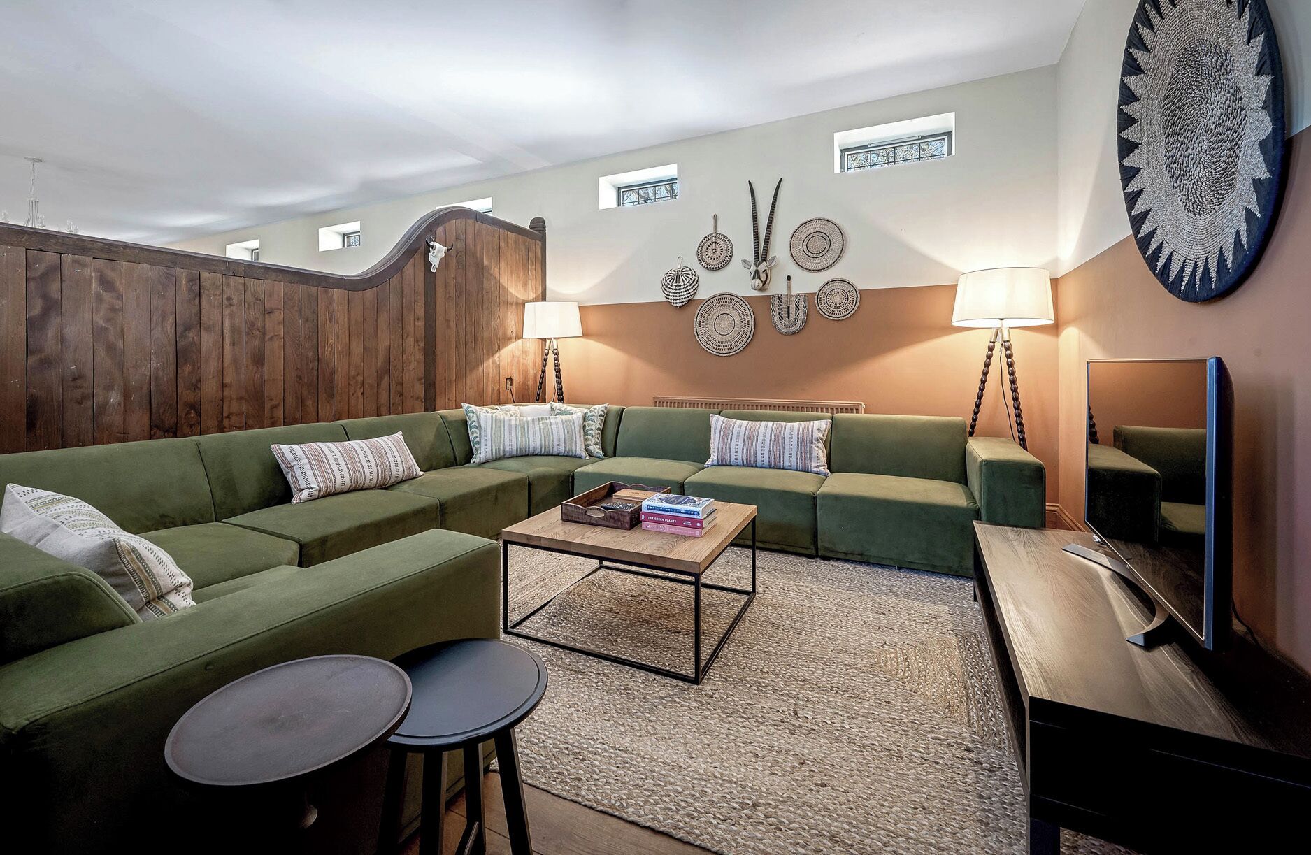 A living room with a sectional sofa, a coffee table, two side tables, a TV, and decorative wall art.