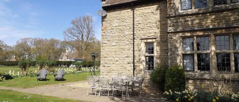 A stone building with a garden patio, outdoor seating, and a view of the surrounding area.