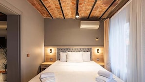 A hotel room with a large bed, two bedside tables, a headboard, and a window with curtains. - Bdıno boutıque hotel (Istanbul)