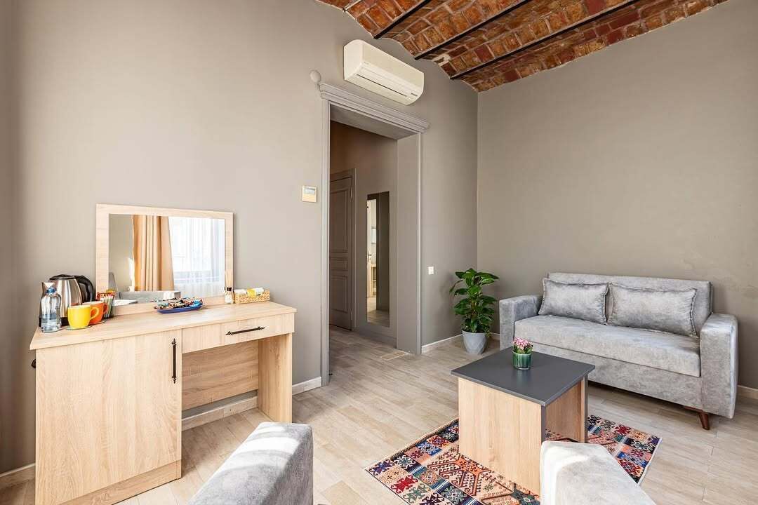 A living room with a sofa, a coffee table, a desk with a mirror, and a potted plant.