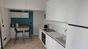 Una cocina compacta con microondas, pileta y un pequeño comedor con sillas.