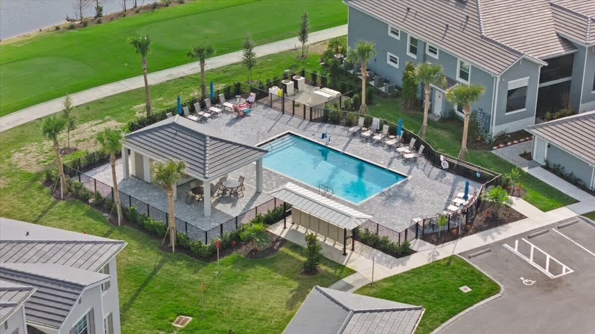 Une propriété résidentielle dotée d’une piscine, d’un patio couvert et d’une pelouse bien entretenue.
