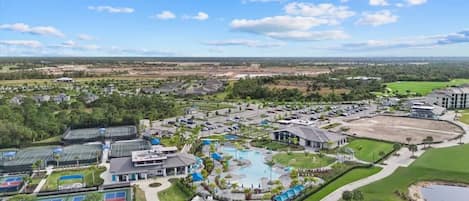 A golf course with a swimming pool, tennis courts, and a large building complex.