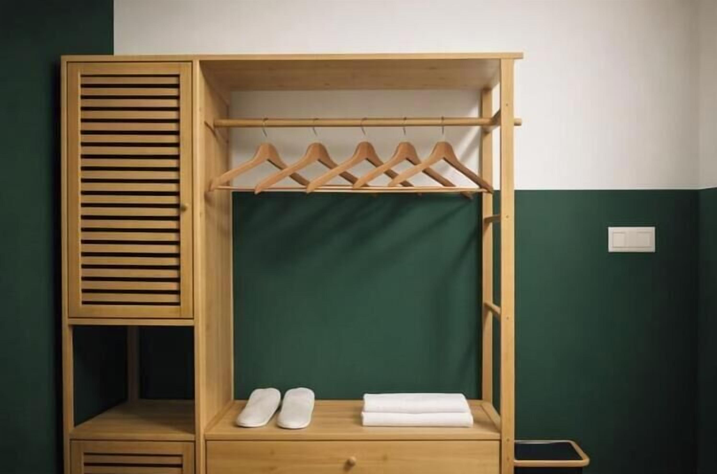 Ein Holzkleiderkasten mit Kleiderstange, einem Schuhregal und einem gefalteten Handtuch.